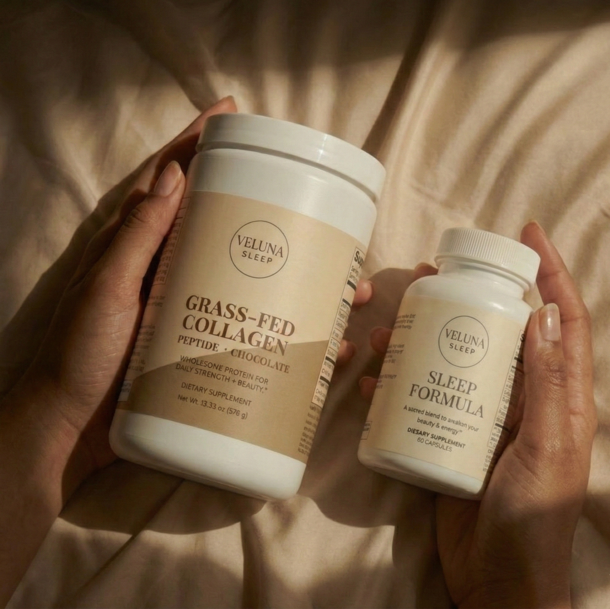 Veluna Deep Restore Booster Bundle, two hands holding the collagen tub and Sleep Formula bottle over bedding