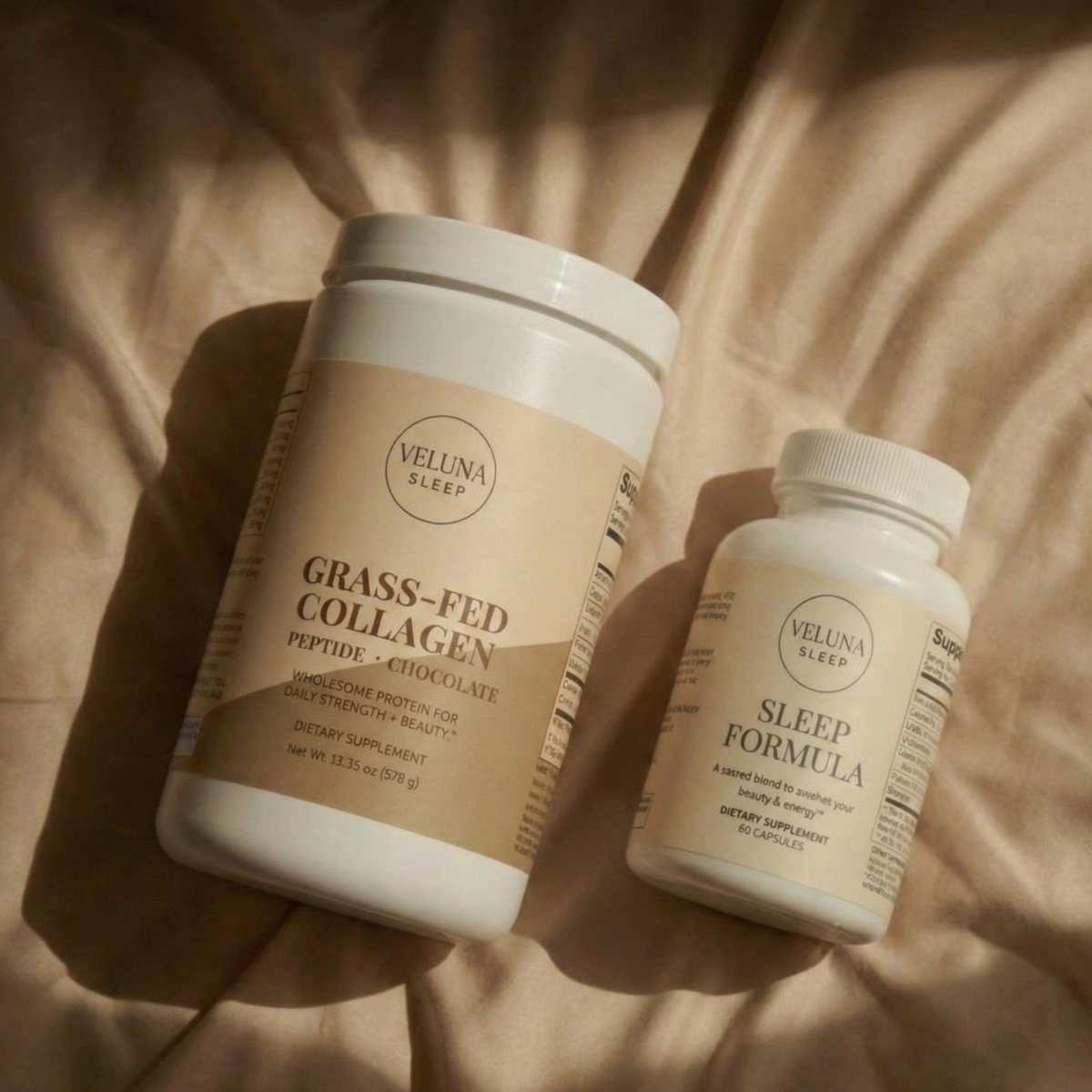 Veluna Deep Restore Booster Bundle, collagen tub and Sleep Formula bottle lying on sunlit cream bedding