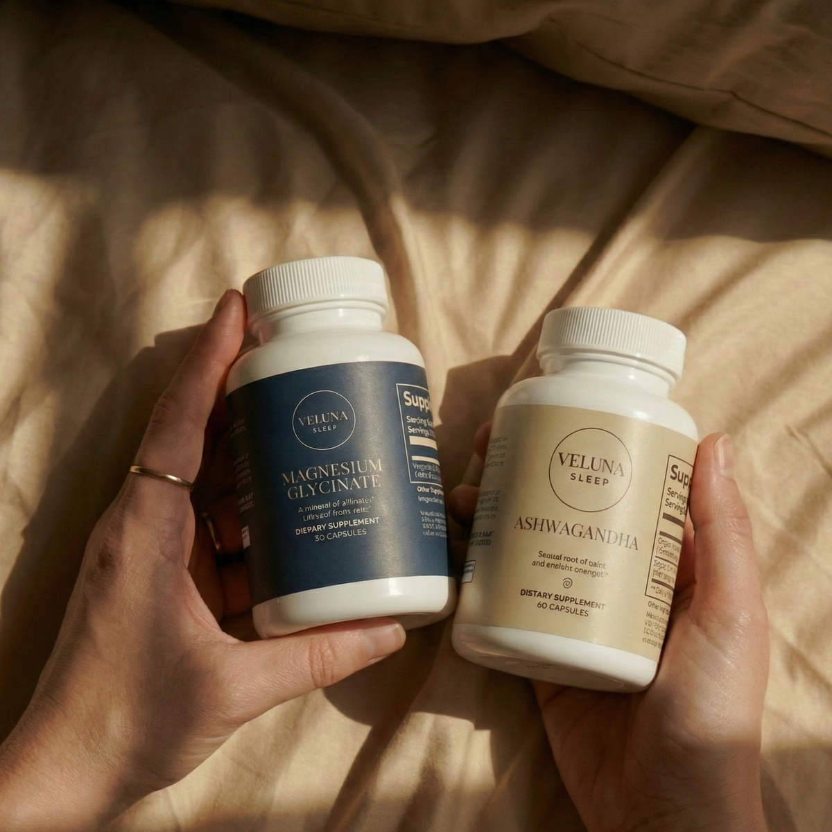 Veluna Mind Calm Starter Bundle, two hands holding the Magnesium Glycinate and Ashwagandha bottles over bedding