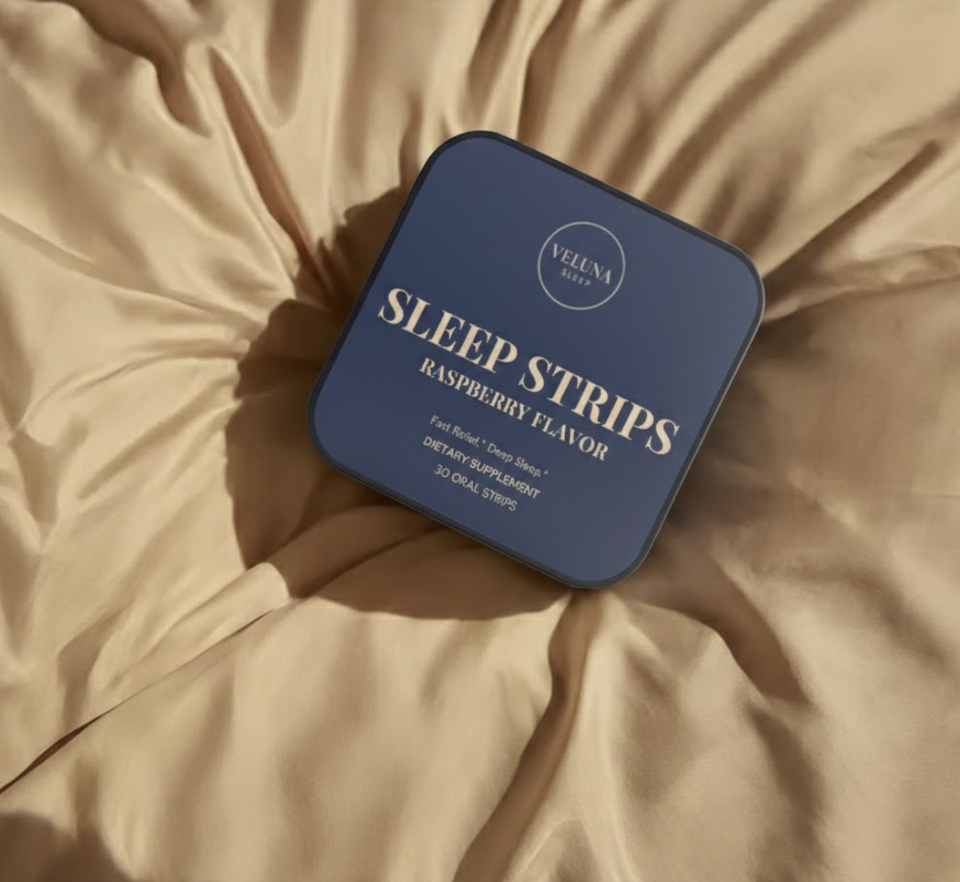 Veluna Melatonin Sleep Strips navy tin lying on rumpled beige satin sheets, seen from above