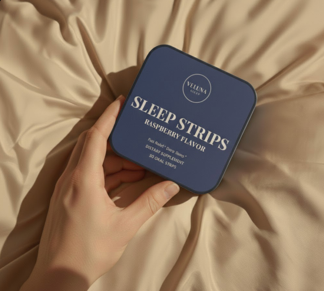 Veluna Melatonin Sleep Strips tin held in one hand over beige satin bedding, close-up