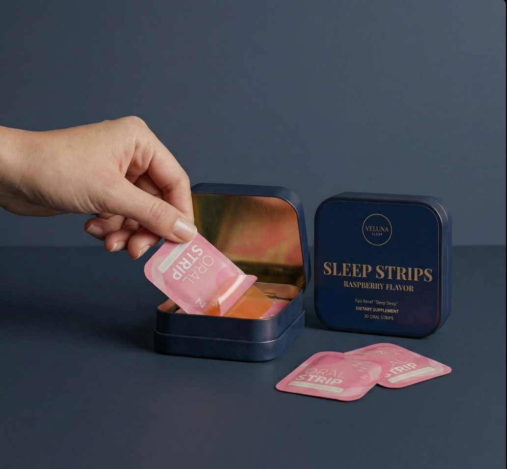 Veluna Melatonin Sleep Strips on navy, a hand pulling a pink pouch from an open tin beside a closed tin