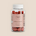 Veluna Hair, Skin & Nails Gummies, clear jar of red gummies with a pink label, pack shot on a warm linen background