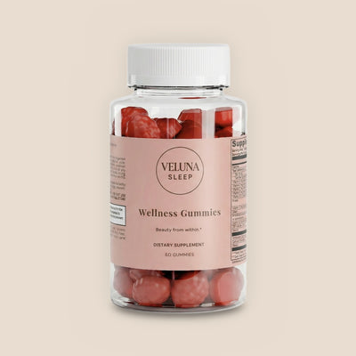 Veluna Hair, Skin & Nails Gummies, clear jar of red gummies with a pink label, pack shot on a warm linen background